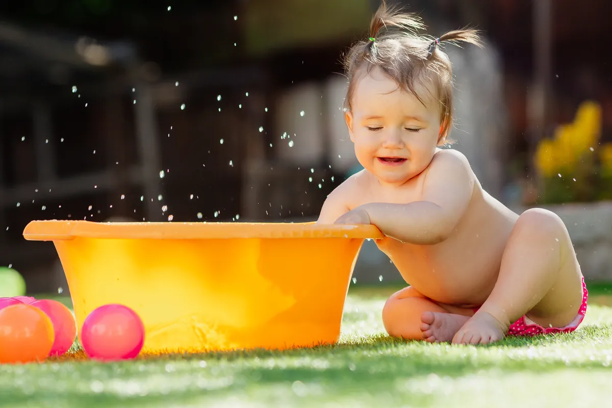 When do babies learn to kick a ball?